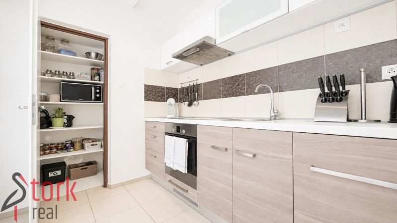 A kitchen with a cooktop and storage space in a 3-room apartment, flooring with a wooden decor.
