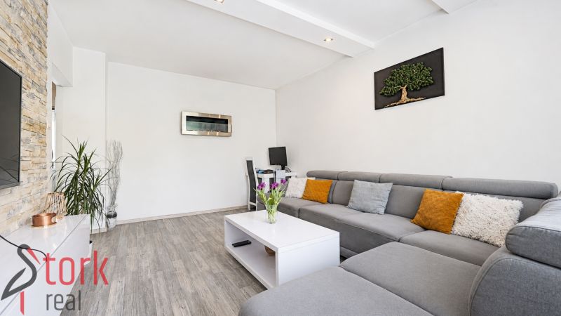Living room in a three-room apartment with a wooden decor floor and a gray sofa.