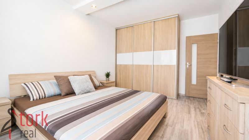 Bedroom with a double bed, wardrobe, and wooden decor flooring in a 3-room apartment.