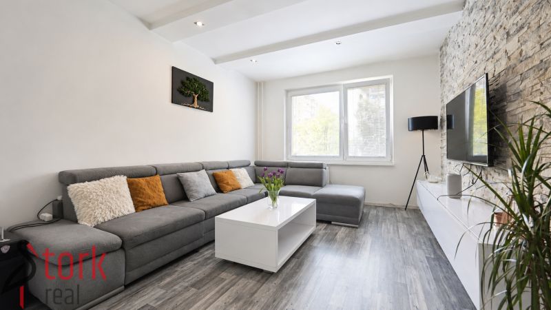Living room with a comfortable sofa, wooden decor flooring, and a decorative wall in a 3-room apartment.