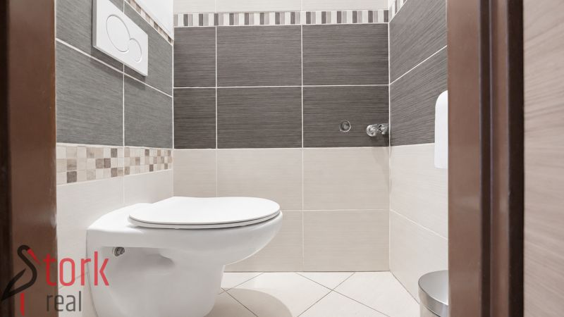 A bathroom in a 3-room apartment with white and gray tiles and light flooring.