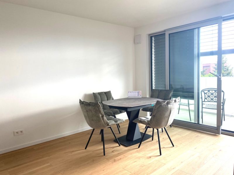Dining table with chairs in an office with wood-patterned flooring.