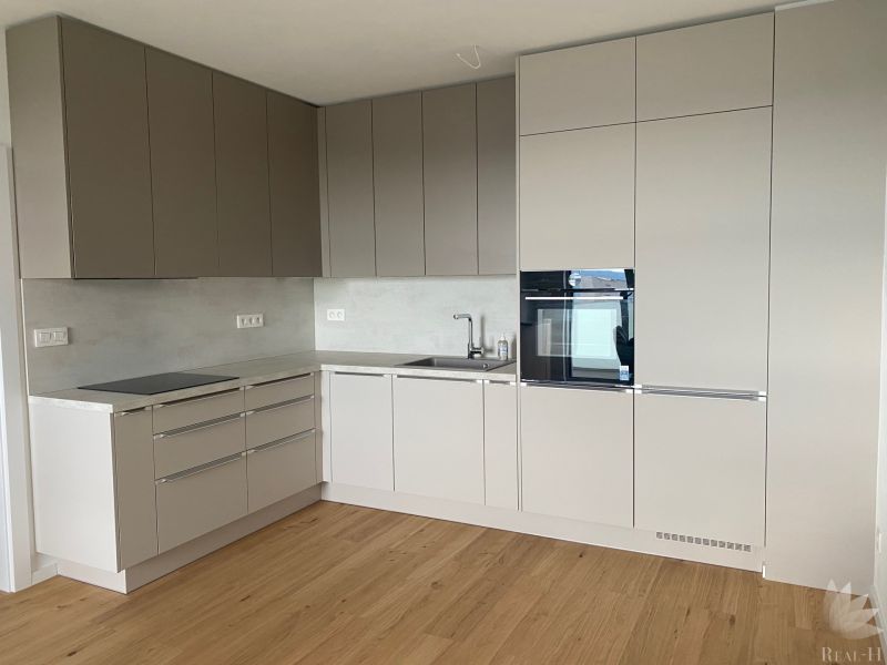 A kitchen with a corner unit, built-in oven, and a floor with wood decor in offices.