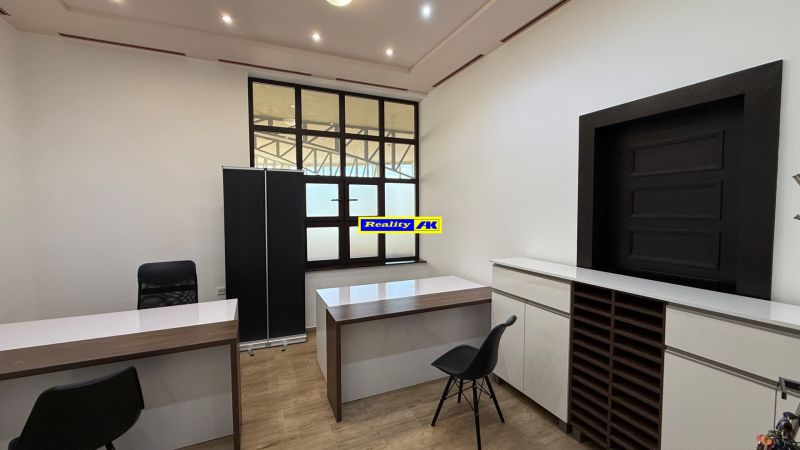 Offices with wood-patterned flooring, simple interior, white walls, black chairs.