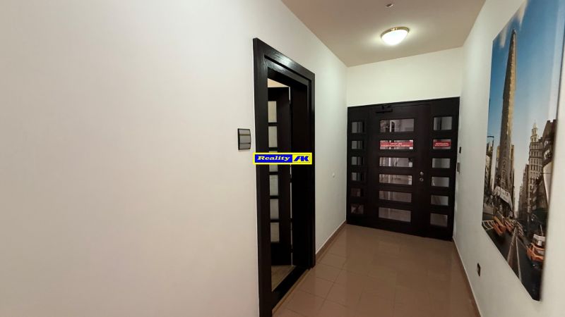 A narrow corridor in office spaces with dark doors and a wood-patterned floor.