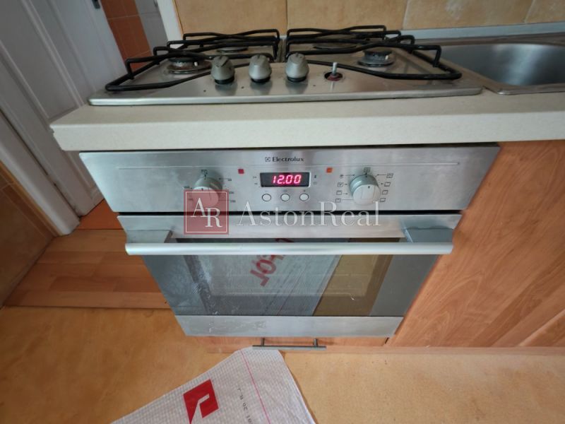 A kitchen with a gas stove and oven, wooden decor flooring in a family house.