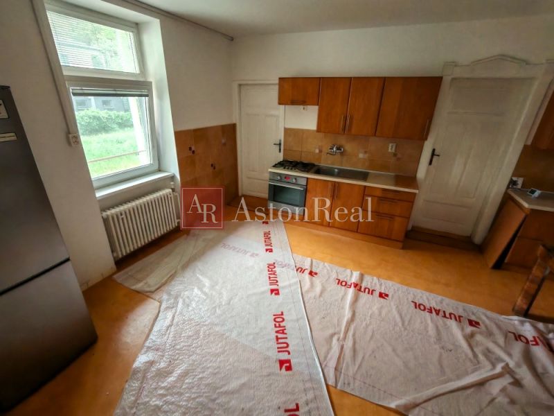 A kitchen in a family house with a wooden floor decor, kitchen unit, and a large window.