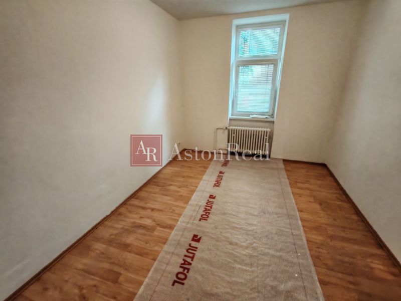 The interior of a room in a family house with a wood-patterned floor and a radiator.