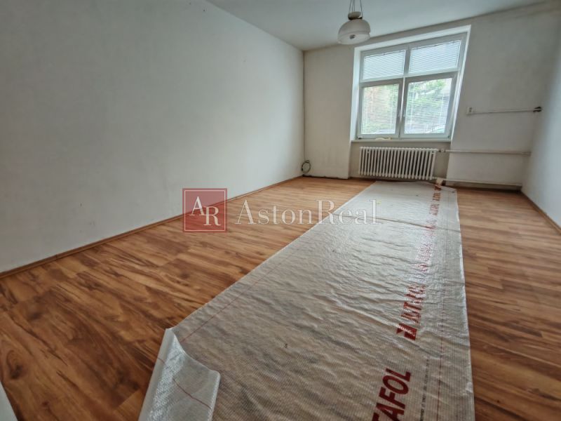 A room in a family house with a wooden decor floor and a large window.