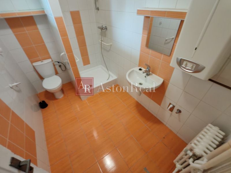 A bathroom in a family house with orange and white tiles and a shower corner.