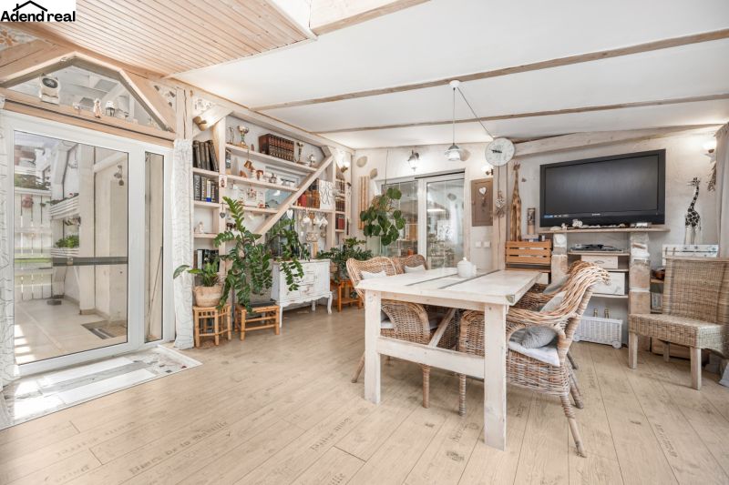Interior of a family house with a wooden decor floor, rattan chairs, and houseplants.