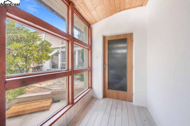 A glazed corridor in a family house with a view of the garden, floor with wooden decor.