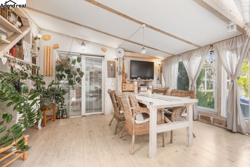 Interior of a family house with rattan furniture, decorative plants, and a floor with a wooden decor.