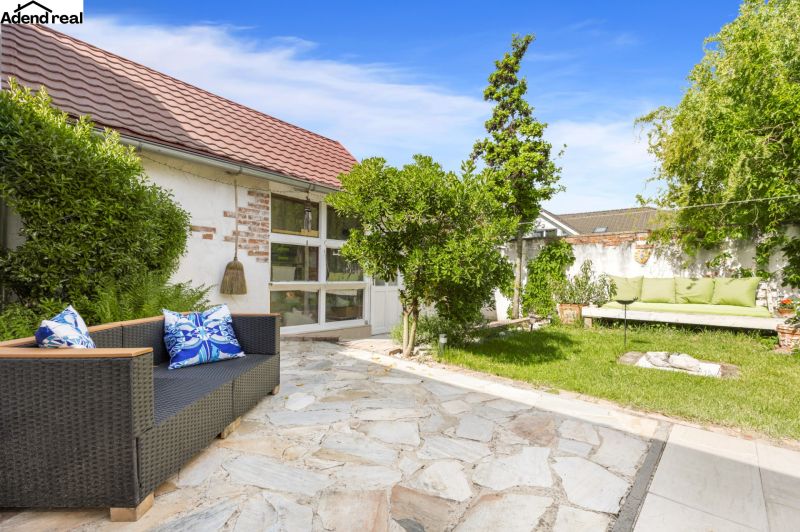 The garden of a family house on Robotnícka Street in Tomášov with a rattan sofa and greenery.