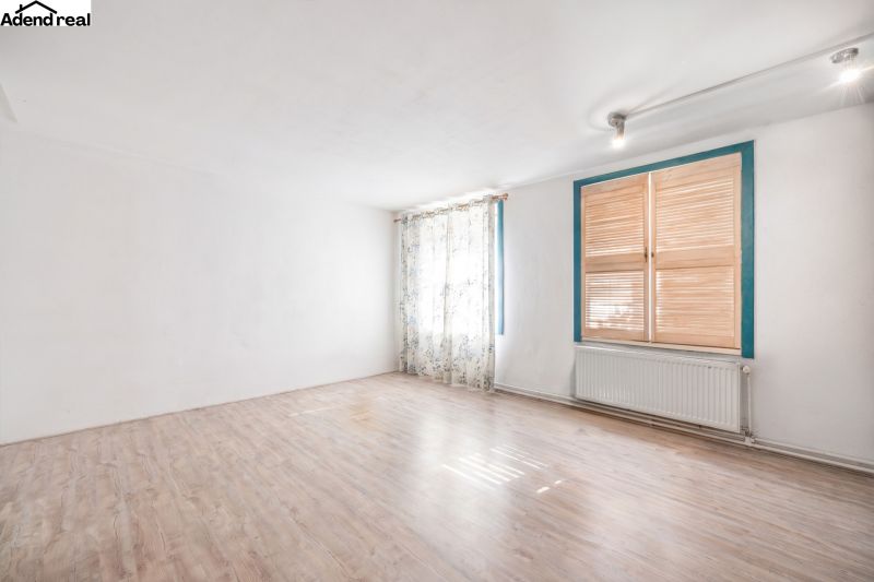 A room in a family house with white walls and a wooden decor floor.