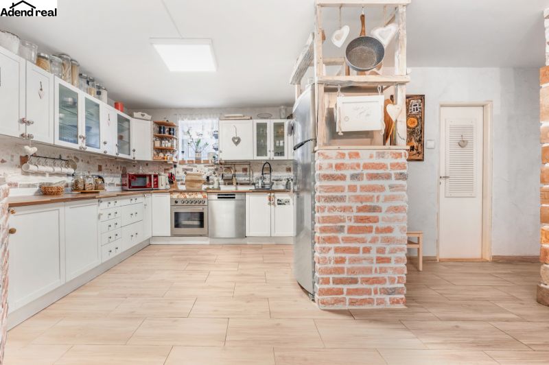 A kitchen in a family house with brick walls and a wooden decor floor.