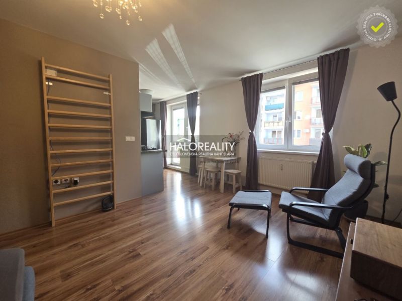 Living room in a two-room apartment with a wooden decor floor and a large window.