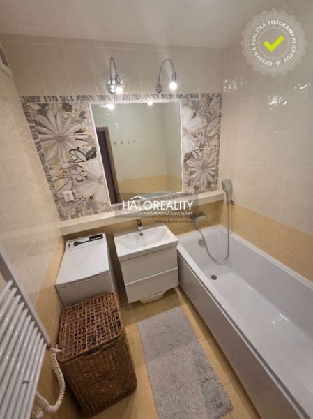Bathroom in a 2-room apartment with a bathtub, washing machine, and tiles.