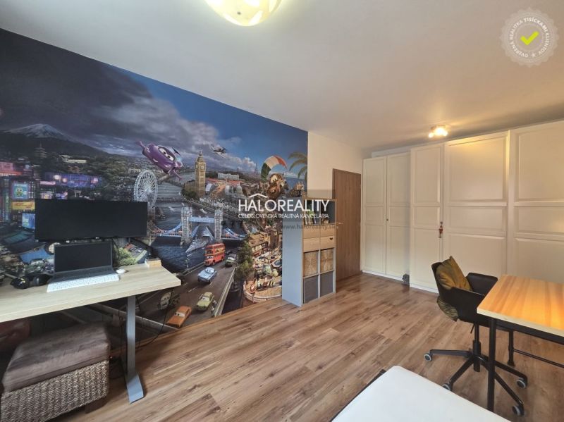 A room with colorful wallpaper and a wooden decor floor in a two-room apartment.