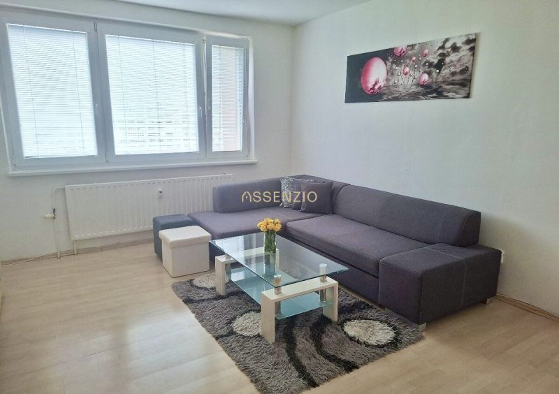 Living room in a 3-room apartment with a sofa, glass table, and wood-patterned flooring.