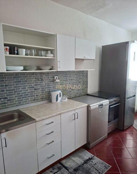 A kitchen in a 3-room apartment with white cabinets and gray tiles.