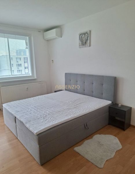 Bedroom in a 3-room apartment with a bed extension and flooring with a wood decor.