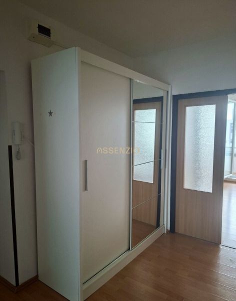 A wardrobe with a mirror in a 3-room apartment with a wooden decor floor.