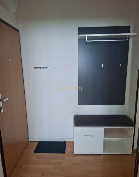 The entrance hall of a 3-room apartment with a wardrobe, a bench, and a wooden decor floor.