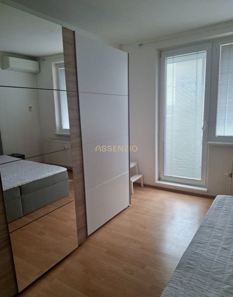 A bedroom in a three-room apartment with a large wardrobe and a wooden decor floor.