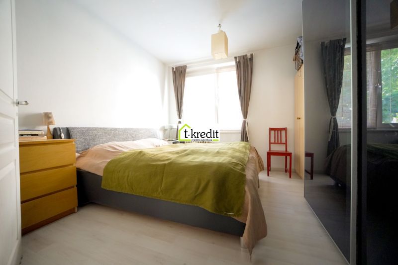 A bright bedroom in a three-room apartment with a comfortable bed and wooden furniture.