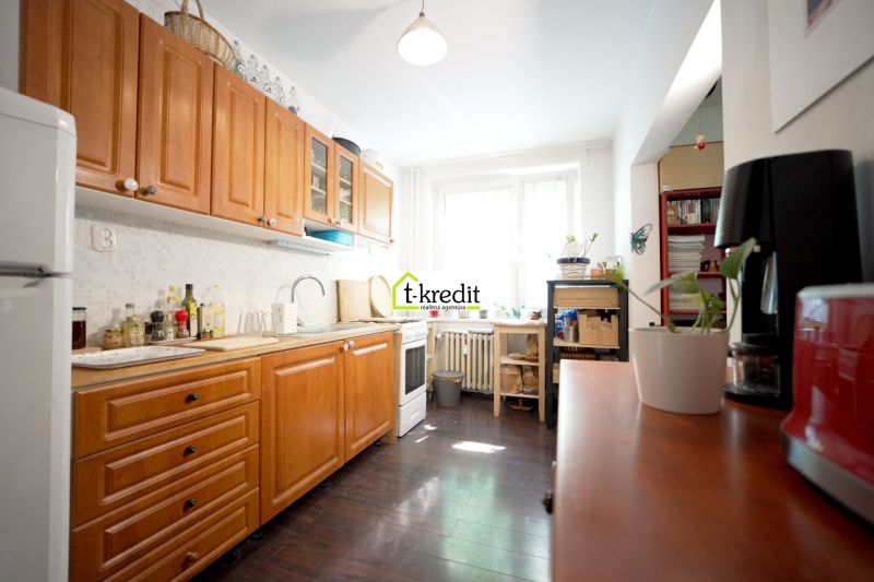 A kitchen in a 3-room apartment with wooden cabinets and a floor with a wooden decor.