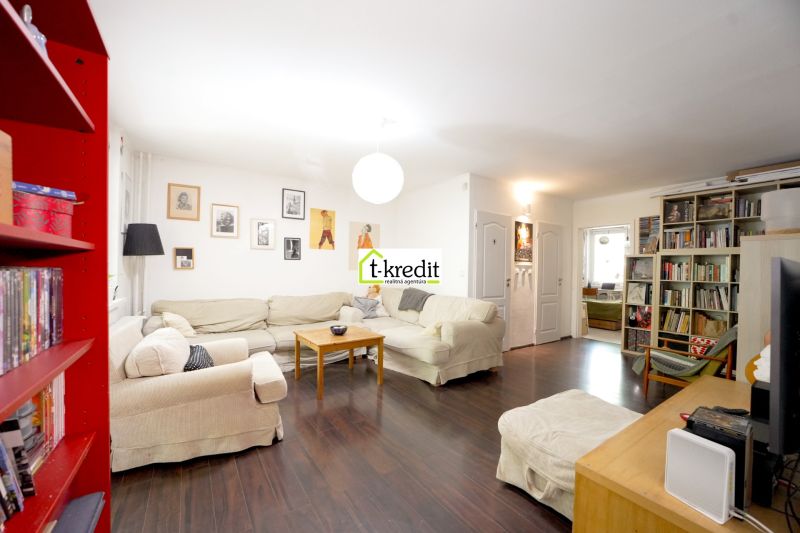 Living room in a 3-room apartment with a sofa, bookshelf, and wooden decor flooring.
