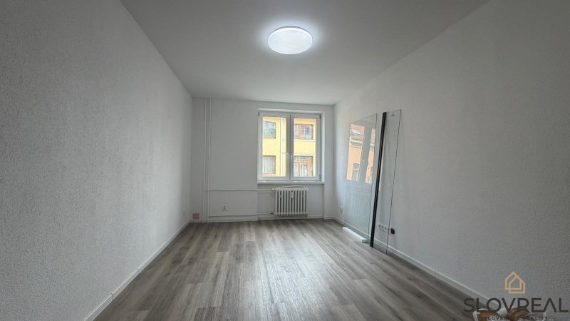 Interior of a 3-room apartment with a wooden decor floor and white walls.