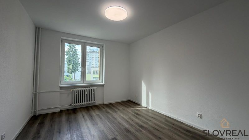 An empty room with a wooden decor floor in a 3-room apartment.