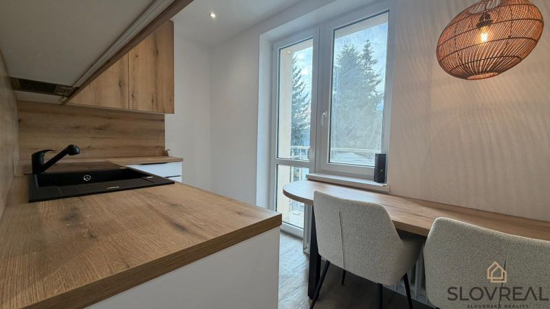 A kitchen in a 3-room apartment with a kitchen unit and a floor with a wood decor.