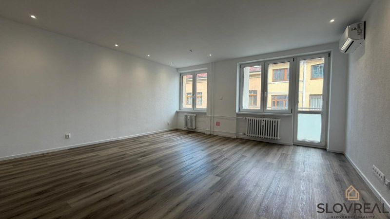 A spacious living area in a three-room apartment with a wooden decor floor.