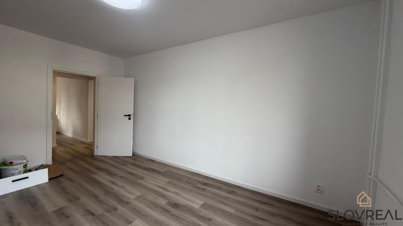 A room with white walls and a wooden decor floor in a 3-room apartment.