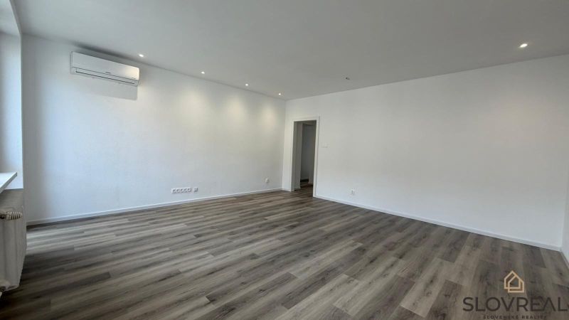 Living room in a 3-room apartment with a wooden decor floor, white walls, and air conditioning.