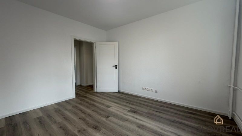 A room with white walls and a wooden decor floor in a 3-room apartment.