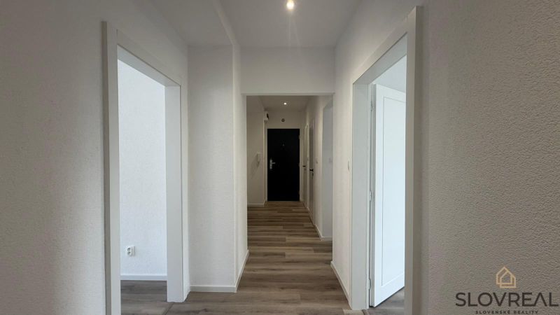 A hallway in a 3-room apartment with a wooden decor floor and white walls.