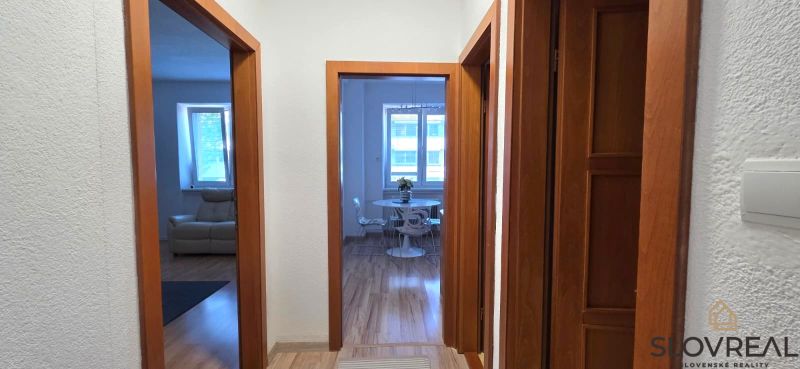 A hallway in a 2-room apartment with a wooden-patterned floor and an armchair.