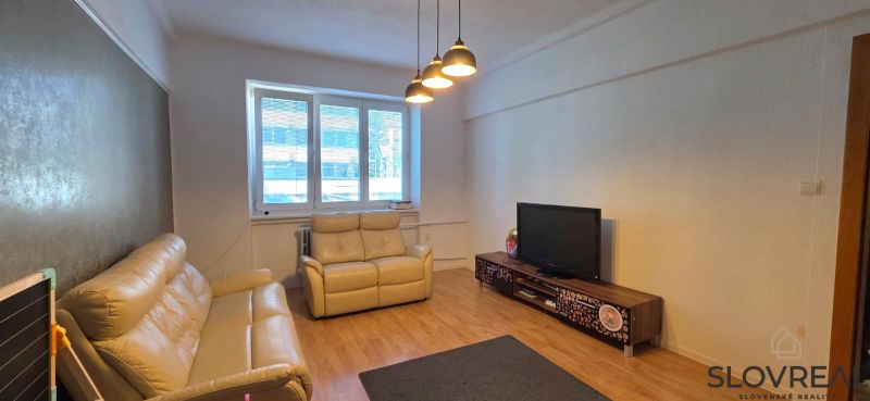 Living room in a 2-room apartment with a wooden decor floor and light furniture.