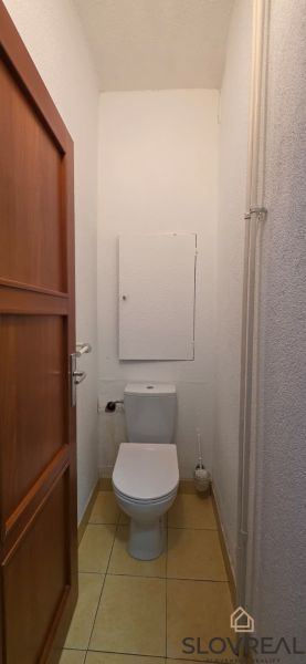 A toilet in a 2-room apartment with simple furnishings and tiles.