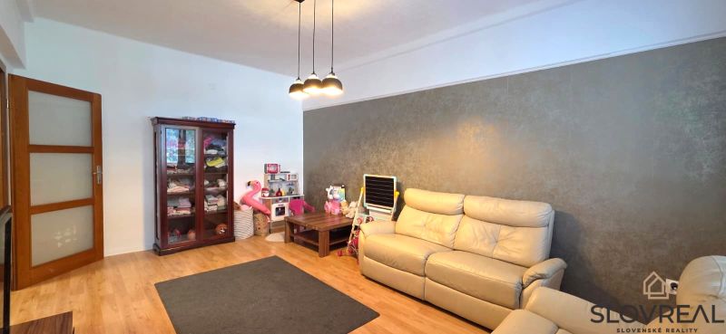Interior of a 2-room apartment with a wooden decor floor, sofa, and cabinet.