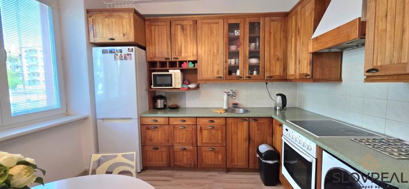A kitchen in a 2-room apartment with a light wood decor and modern appliances.