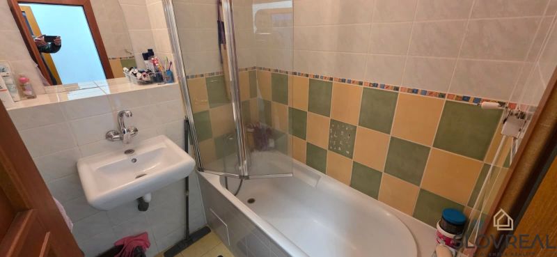 Bathroom in a 2-room apartment with a bathtub and colorful wall tiles.