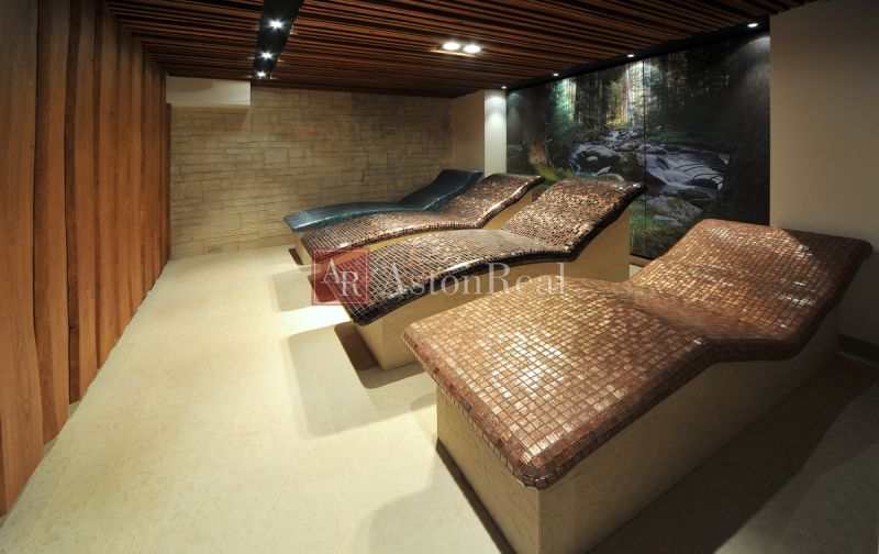 Loungers in a recreational apartment with stone decor and a wooden wall.