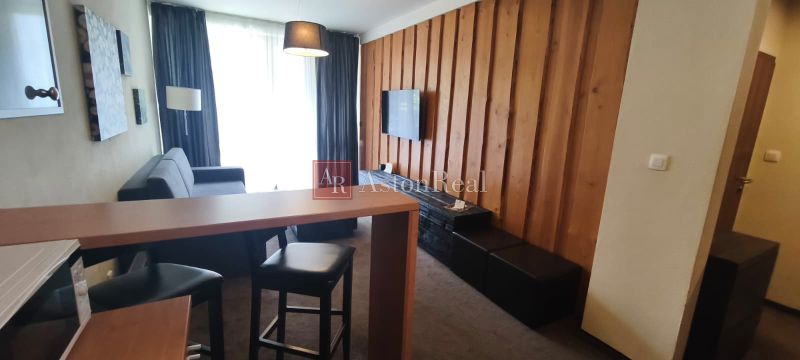 Living room of a holiday apartment with wooden paneling and wood-patterned flooring.
