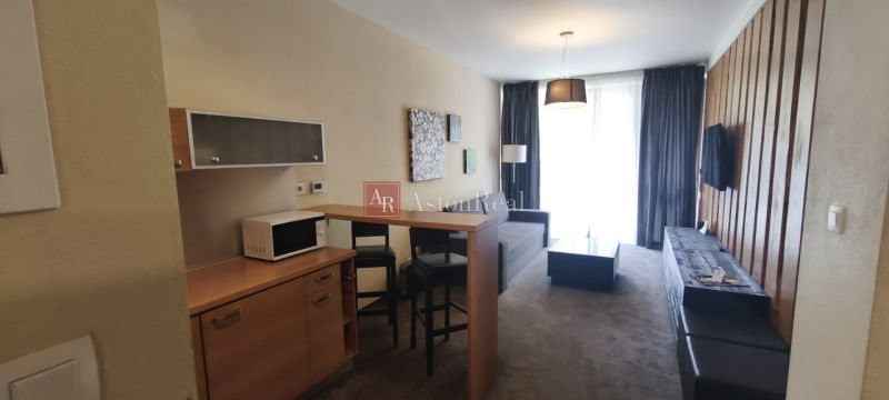Interior of a vacation apartment with a sofa, microwave, and a bar table with two chairs.