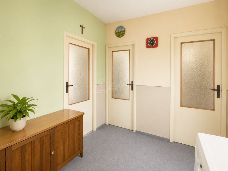 A hallway in a 3-room apartment with a wooden chest of drawers and a green wall.